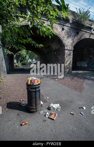 overflowing rubbish bin in park Stock Photo