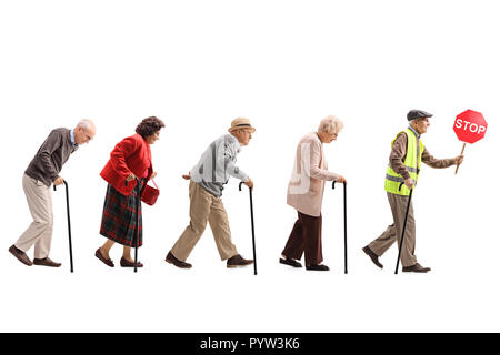 Full length shot of senior people walking in a line behind an elderly man with a safety vest and stop sign isolated on white background Stock Photo
