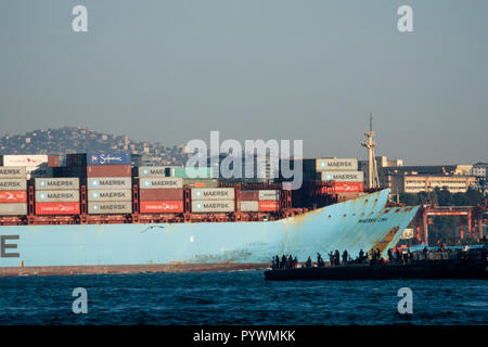 Container ship passes crowd of recreational fishermen on the Bosphorus at it passes through Istanbul, Turkey Stock Photo