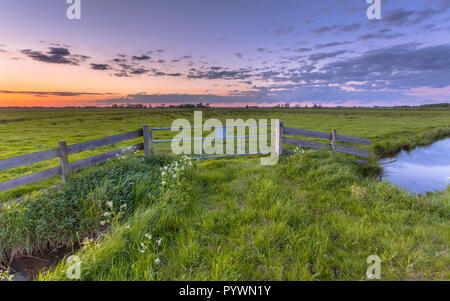 Purple sunset over fence in dutch polder landscape near Groningen Stock Photo