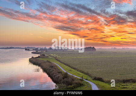 Aerial view of Netherlands Polder landscape with winding cycling track along river under beautiful sunset Stock Photo