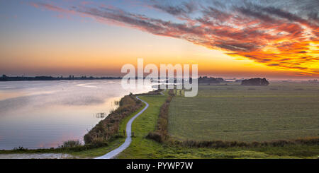 Aerial panorama of Netherlands Polder landscape with winding cycling track along river under beautiful sunset Stock Photo