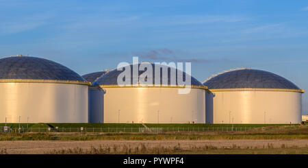 Modern big oil storage tanks in an industrial harbor area at sunset with blue sky in the Netherlands Stock Photo