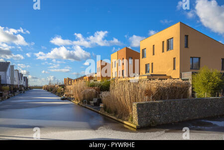 Modern futuristic family houses along a canal in winter setting with snow and ice, Groningen, Netherlands Stock Photo
