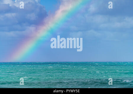 Rainbow in the ocean after rain and thunderstorms. Colorful views of the rainbow against the sky, clouds and sea horizon. Stock Photo