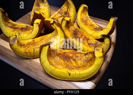 Closeup with baked pumpkin slices covered in rum and brown sugar as dessert for Halloween dinner Stock Photo