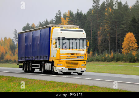 Salo, Finland - October 12, 2018: Yellow and white DAF XF semi truck at speed on freeway in South of Finland on a foggy day of autumn. Stock Photo