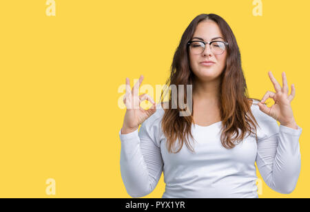 Young beautiful plus size woman in pink sporty top and leggings sitting on  orange yoga mat dreamily looking aside while spending time in park Stock  Photo