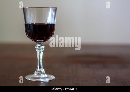 Glass of wine under wooden table Stock Photo