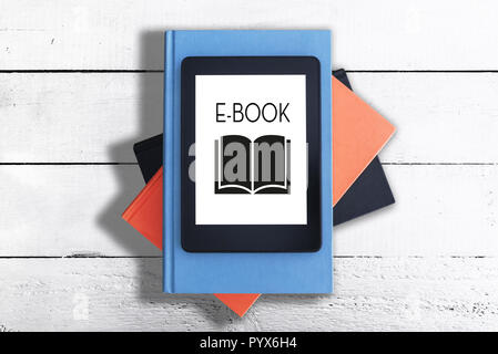 e-reader on stack of books against white rustic wooden table Stock Photo