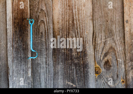 Painted blue lock hook hanging on the old brown wooden door. Stock Photo