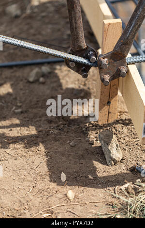 Worker Using Tools To Bend Steel Rebar At Construction Site. Stock Photo