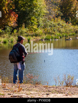 Fairfax, VA, USA--October 30, 2018. A man is fishing from the banks of Lake Royal in Fairfax VA on an Autumn afternoon. Stock Photo