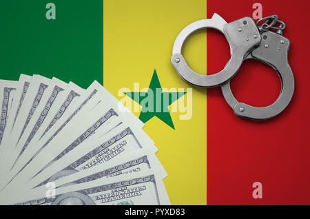 Senegal flag  with handcuffs and a bundle of dollars. The concept of illegal banking operations in US currency. Stock Photo