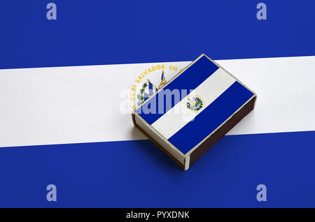 El Salvador flag  is pictured on a matchbox that lies on a large flag. Stock Photo