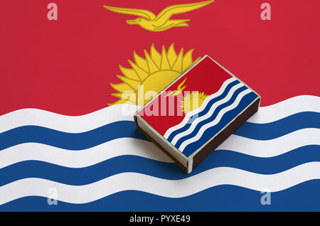 Kiribati flag  is pictured on a matchbox that lies on a large flag. Stock Photo