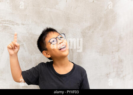 Little asian boy smiling with finger pointing upward. Stock Photo