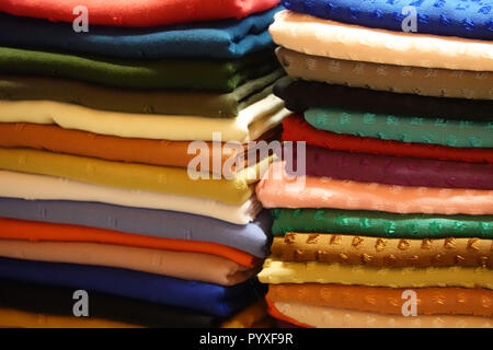 Stack with cloths and fabric in many different colours in one stall Stock Photo