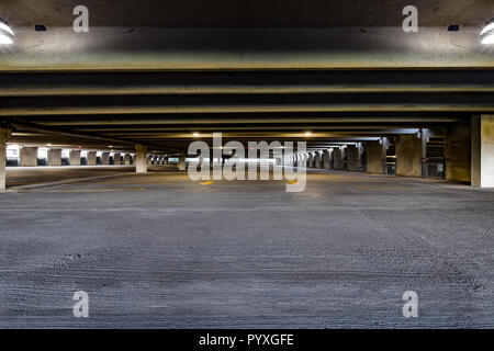 Underground empty parking garage with overhead lights and an exit sign ...