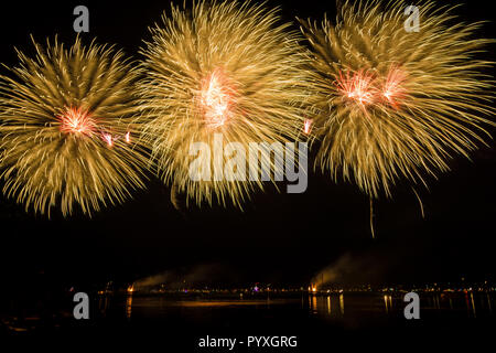 Three orange huge fireballs of amazing fireworks rocket explosions in the night Stock Photo