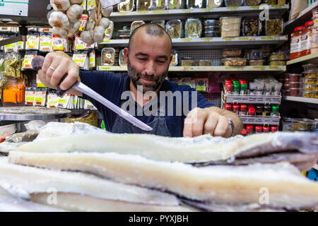 Spanish fishmonger in Malaga central market slicing bacalao, Spain Stock Photo