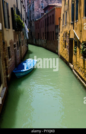 A boat moored in a sunlit section of canal, Venice, Italy Stock Photo