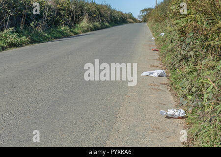 Stretch of litter-strewn country lane. Concept roadside litter UK. Keep Britain tidy, plastic waste in road. For Clean Up Britain campaign. Stock Photo