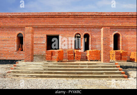 Bricks on pallets near the wall of the building under construction Stock Photo