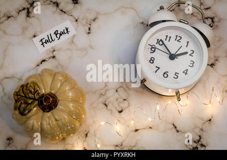 Fall Back Daylight Saving Time concept with white clock and autumn leaves, flat lay on marble Stock Photo