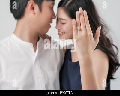 Happy woman showing engagement ring after proposal while is cuddling her boyfriend. Stock Photo