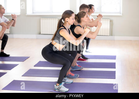 Group of people doing squatting standing in row at gym Stock Photo