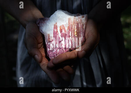 Close up of a woman holding a pink tourmaline in quartz crystal in powerful healing concept. Stock Photo