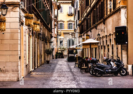 Scooters and a street cafe in a typical narrow Rome street Stock Photo