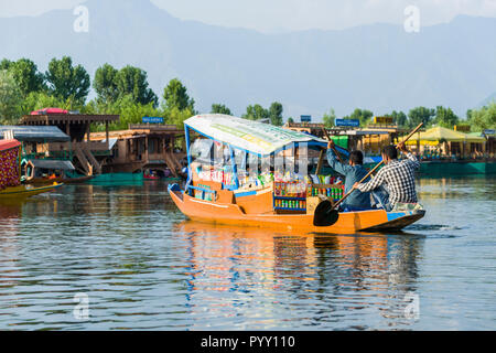 Shikaras are the common transport for people and goods on Dal Lake. Houseboats for rent are seen in the background Stock Photo