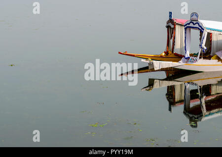 Shikaras, mirroring in the water, are the common transport for people and goods on Dal Lake Stock Photo