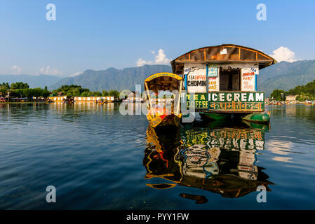 Shikaras are the common transport for people and goods on Dal Lake. Houseboats for rent are seen in the background Stock Photo