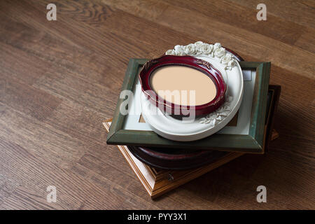 perspective view of stack wood vintage frames of all shapes colors and seizes on dark brown wooden parquet floor background Stock Photo