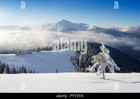Mountain huts on a snowy hill. Winter landscape on a sunny day Stock Photo