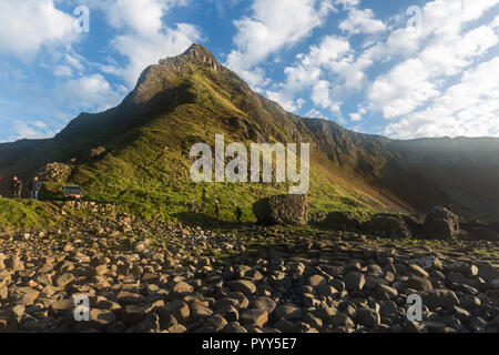 Looking back from the Causeway to the headland behind in bright sunshine with blue skies and white clouds. Giants Causeway, County Antrim, N.Ireland. Stock Photo