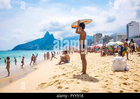 RIO DE JANEIRO - CIRCA MARCH 2018: A young Brazilian man stands holding a skimboard on his head as he scans the shore of Ipanema Beach Stock Photo