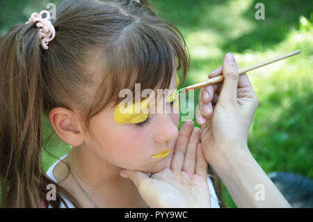 Master body art puts the girl drawing paints on the face. Stock Photo