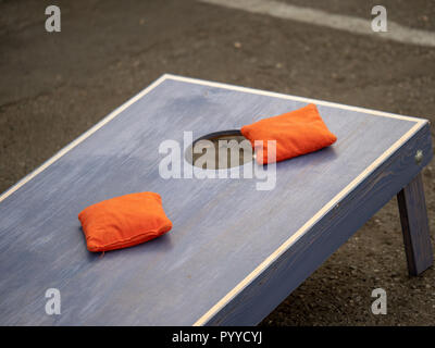 Orange beanbags sitting on blue cornhole board platform Stock Photo
