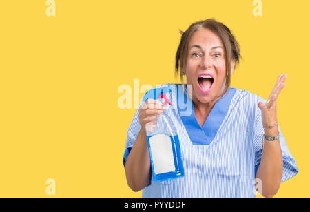 Middle age brunette cleaner woman wearing housework uniform over isolated background very happy and excited, winner expression celebrating victory scr Stock Photo