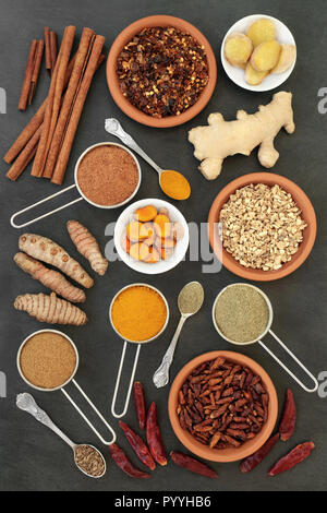 Spices for losing weight with turmeric, cumin, ginger, chilli, cinnamon and gymnema sylvestre used to suppress appetite. Top view on slate background. Stock Photo