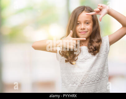Brunette hispanic girl smiling making frame with hands and fingers with happy face. Creativity and photography concept. Stock Photo