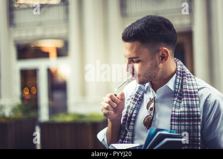 Stylish young businessman is lighting a cigarette in the city Stock Photo