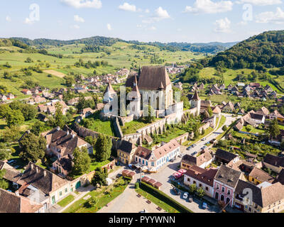 Biertan town and fortified church in Transylvania, Romania. Medieval castle on a hill, high spires, walls, red tiled roofs, surrounded by a village. Stock Photo