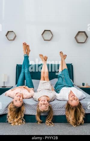 happy three generations of women lying on bed and looking at camera Stock Photo