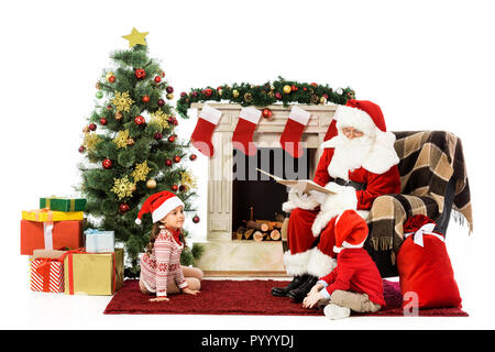 santa reading book for kids while sitting in armchair isolated on white Stock Photo