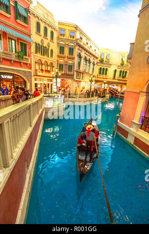 Macau, China - December 9, 2016: gondolier sings famous italian songs to tourists during a romantic ride in gondola on Grand Canals of Shoppes at the Venetian Luxury Hotel and Casino. vertical shot Stock Photo